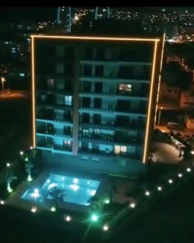 Wellness Suite gece, havadan: ışıklı çerçeveli cephe ve havuz